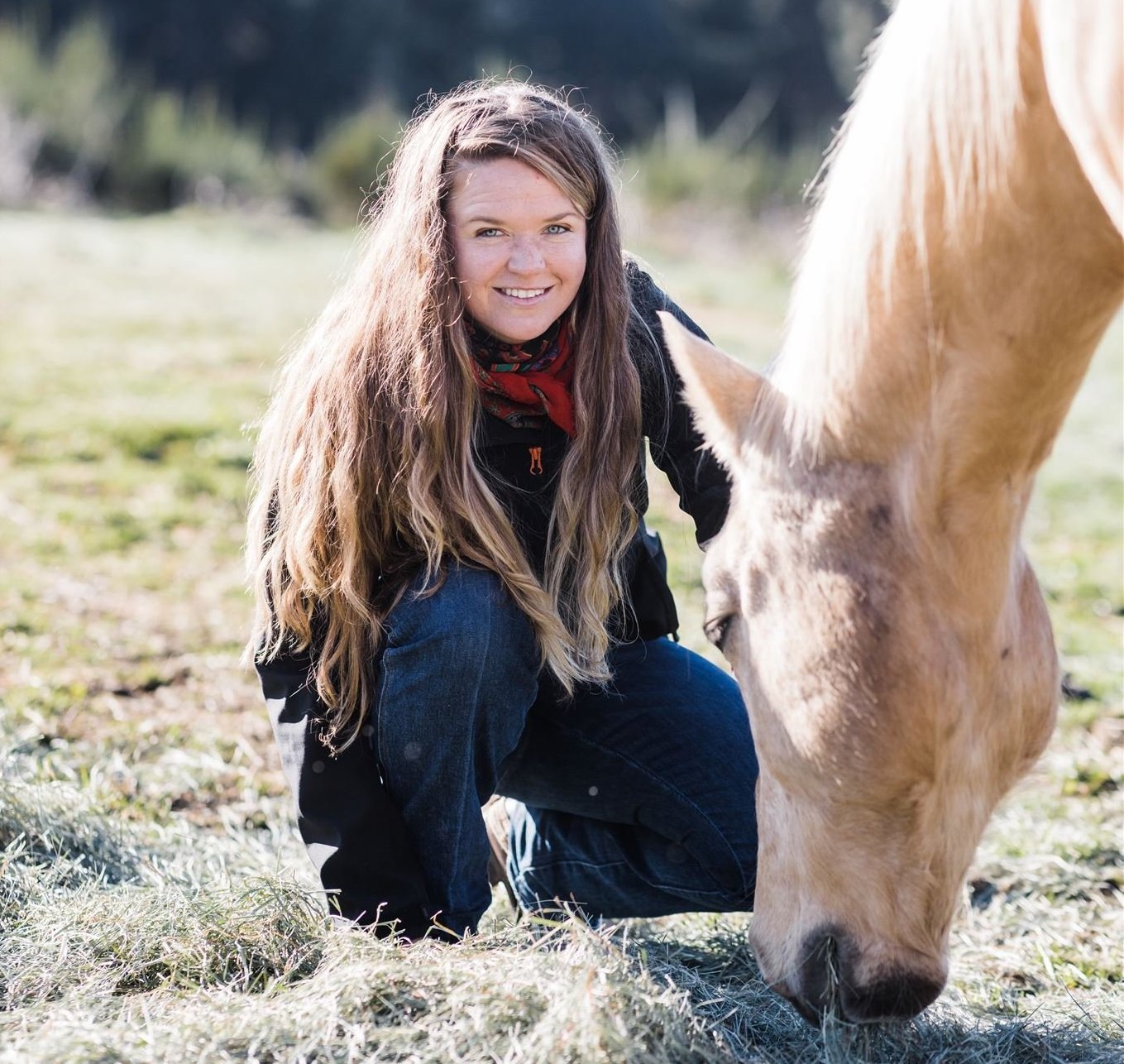 Chessy Jones kneels with a horse.
